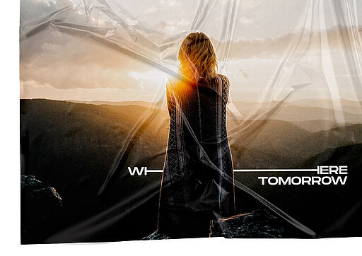 Deutsch (Alt-Text / SEO): Frau auf einem Berg im Sonnenuntergang oder Sonnenaufgang, Blick in die Weite. Hinter ihr ist das Where Tomorrow Is-Logo großflächig platziert und horizontal gestreckt – visuelles Beispiel für das dynamische Logo und das variable „H“. English (Alt text / SEO): Woman standing on a mountain at sunset or sunrise, looking into the distance. Behind her, the Where Tomorrow Is logo is stretched across the scene, showcasing the dynamic logo system and its flexible “H”.