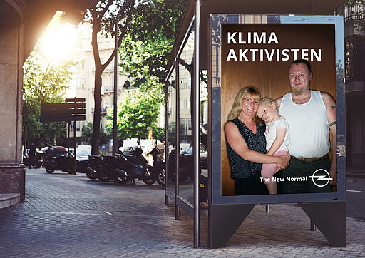 Deutsch – Bildbeschreibung (SEO / Google-Kampagne) Motiv aus der Kampagne „The New Normal“ für Opel. Zu sehen sind zwei Eltern mit einem Kleinkind in einer alltäglichen, bürgerlichen Situation. Über dem Bild steht der Schriftzug „Klimaaktivisten“. Die bewusste Diskrepanz zwischen Zuschreibung und Darstellung erzeugt einen humorvollen Perspektivwechsel und verankert Elektromobilität im normalen Familienalltag. ⸻ English – Image description (SEO / Google campaign) Visual from the “The New Normal” campaign for Opel. The image shows two parents with a young child in an ordinary family setting. Above the image, the caption reads “Klimaaktivisten”. The contrast between the label and the everyday scene creates a subtle humorous shift, positioning electric mobility as part of normal family life.