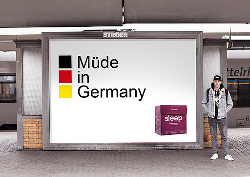 Deutsch (Alt-Text / SEO): Plakatwerbung für Solid „Sleep“: violette Verpackung eines Schlafprodukts, daneben der Slogan mit Wortspiel „müde in Deutschland“ statt „made in Deutschland“. English (Alt text / SEO): Billboard ad for Solid “Sleep”: a purple pack of a sleep product, featuring the slogan wordplay “müde in Deutschland” instead of “made in Germany”.